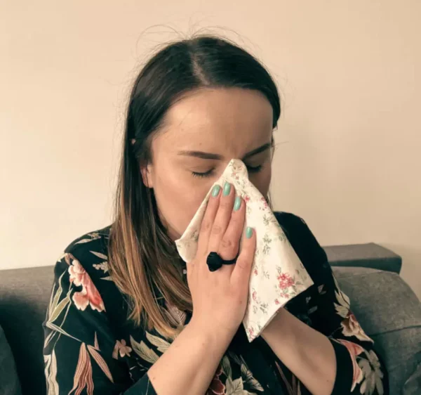 Kobieta wydmuchujca nos w materiałowa kwiecista chusteczke